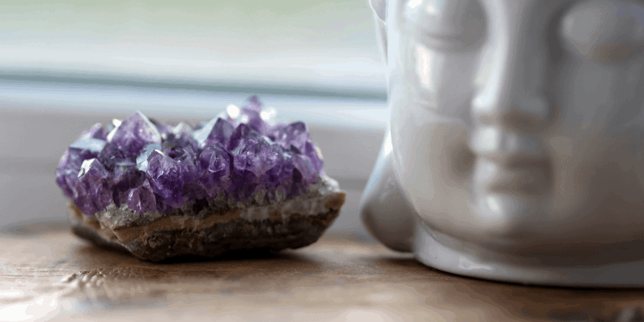 Decorative image of an amethyst crystal next to a statue head