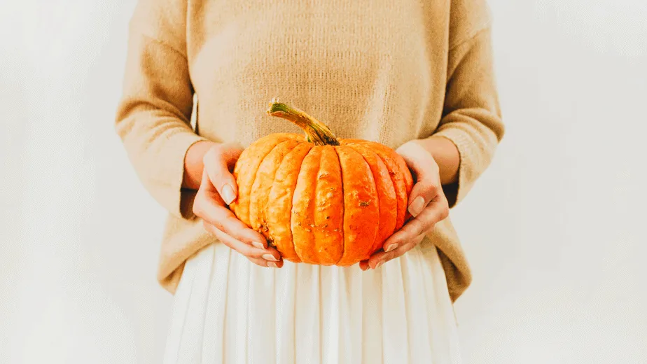 Decorative image of a woman holding a pumpkin for Mabon