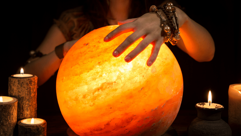 Decorative image of a psychic woman with a himalayan salt lamp crystal ball and rustic candles