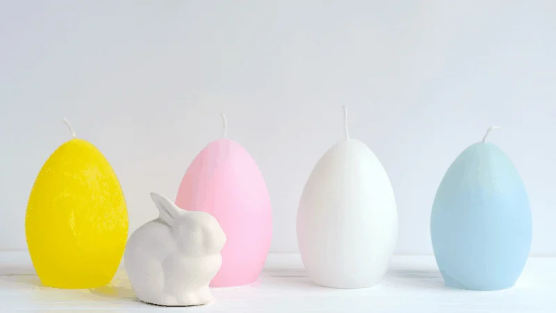 Egg candles in pastel colors with a white ceramic bunny rabbit.