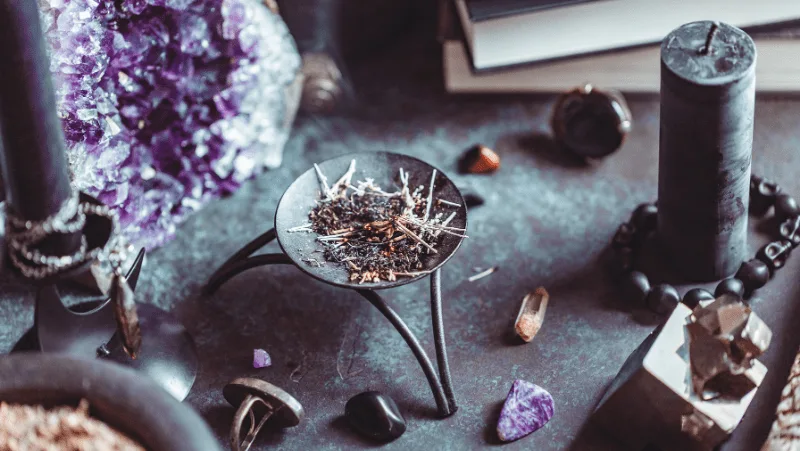 Witch supplies on an altar, including incense, crystals, jewelry, and candles