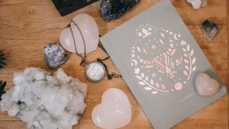 Rose quartz and other crystals on a flat lay with a taurus journal