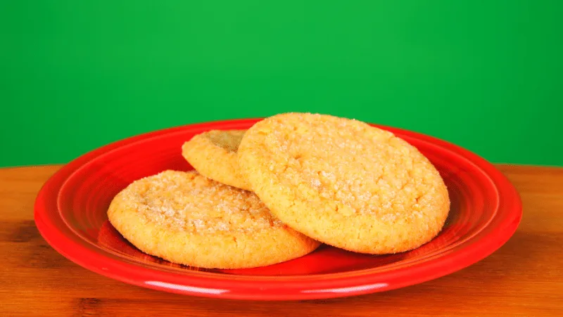 Sugar cookies on a red plate with a green background.