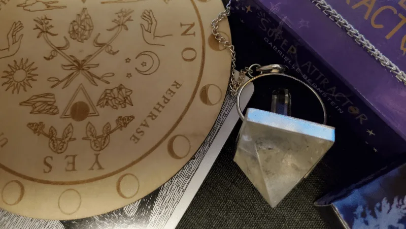 A magical pendulum, a tarot card, and a wooden pendulum board from Tamed WIld