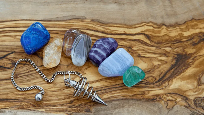 A silver pendulum and 7 colorful spiritual crystals for healing