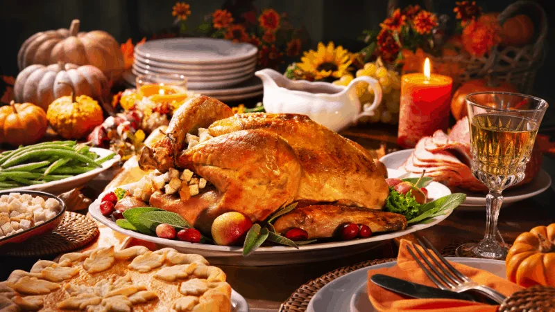 What do witches do for Thanksgiving? They eat turkey like this one in this image, surrounded by other Thanksgiving foods and drinks and a lit candle