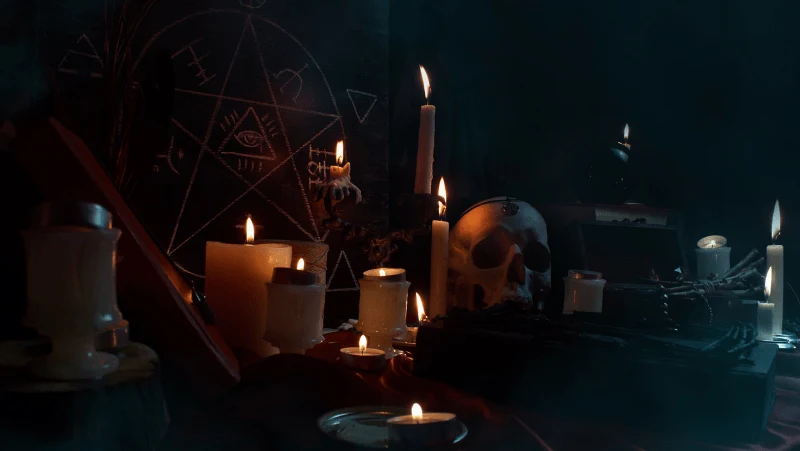 A table set with witchy tools like a skull, pentagram, candles, and more