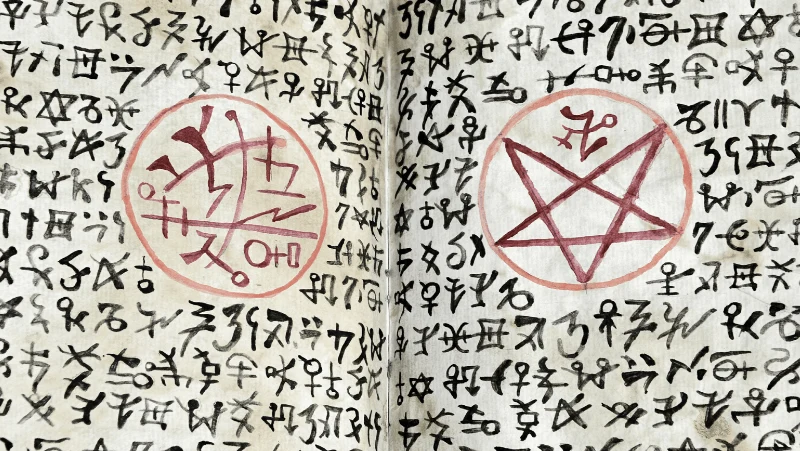 The Theban alphabet and other cipher systems in a witch's book of shadows with a red pentagram and a sigil