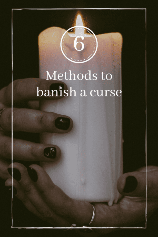 Methods to break a magic curse or hex. Woman holding a candle with black nails. A white star and moon are painted on one nail.
