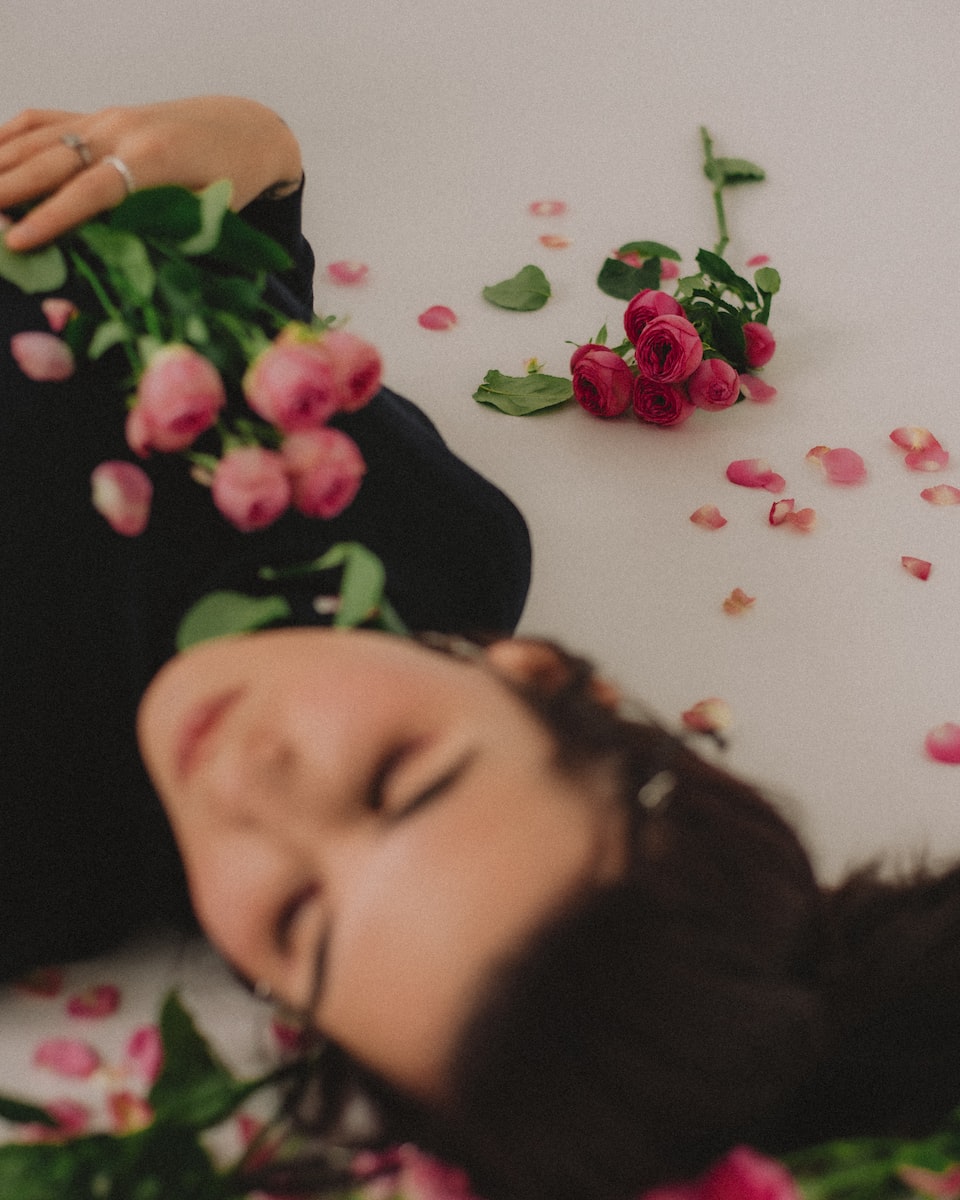 a woman laying on the ground with flowers around her