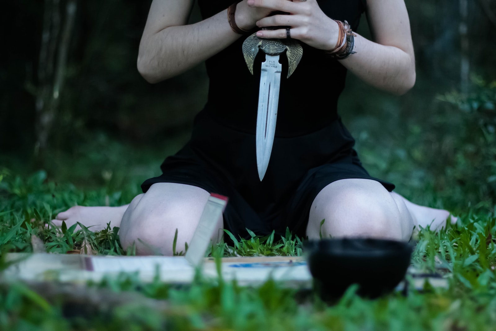 woman kneeling on grass holding knife