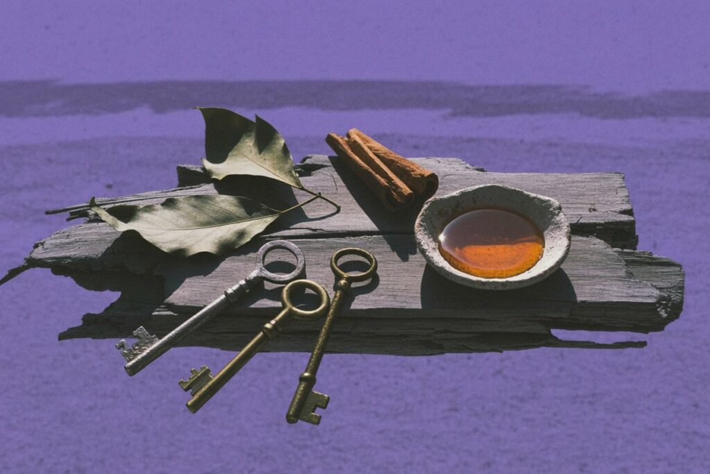 Antique brass keys rest on sun-bleached driftwood alongside cinnamon sticks, bay leaves, and honey—the herbs and offerings mentioned in the post's practical work section. The keys represent Hekate's role as Keeper of Keys to all realms, while the solar correspondences ground her summer practice in tangible ritual elements.