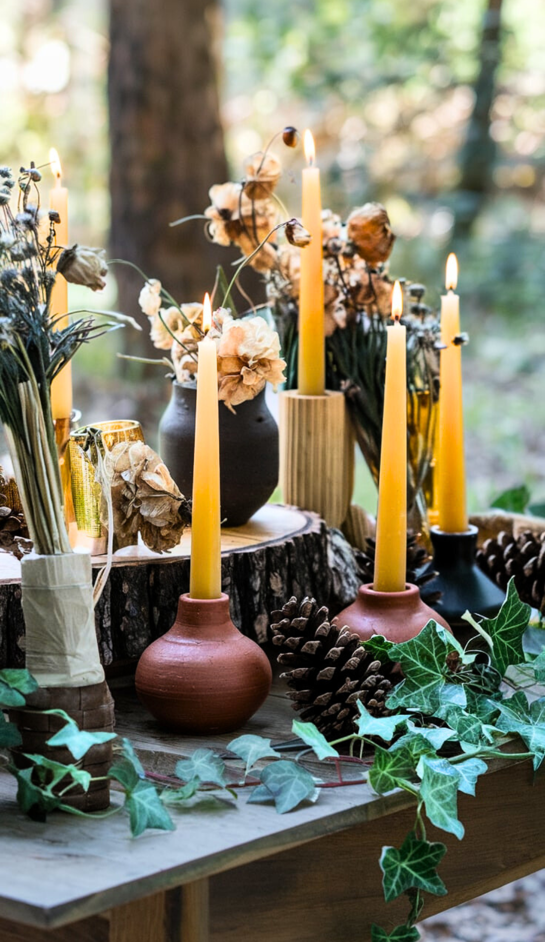 Rustic altar setup with beeswax candles and dried flowers on a wooden table in a natural outdoor setting. This image highlights an earthy and sustainable altar design for Imbolc celebrations, perfect for readers seeking eco-friendly and natural decor ideas.